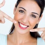 A woman smiling widely, showing her teeth after visiting Andrew Baderski Dental for a check-up.