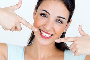 A woman smiling widely, showing her teeth after visiting Andrew Baderski Dental for a check-up.