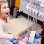Andrew Baderski Dental - a happy child playing with fake teeth in a dental clinic