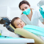 A child smiling while sitting on a dental chair at Andrew Baderski Dental.