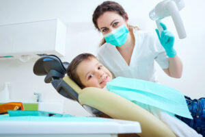 Andrew Baderski Dental - a child smiling while sitting on a dental chair