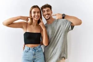 A happy couple pointing their perfect smile after their treatment at Andrew Baderski Dental