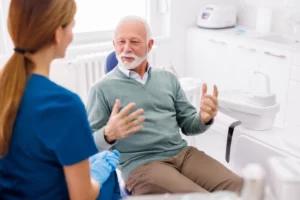 The dentist at Andrew Baderski Dental is explaining the treatment to the old man patient